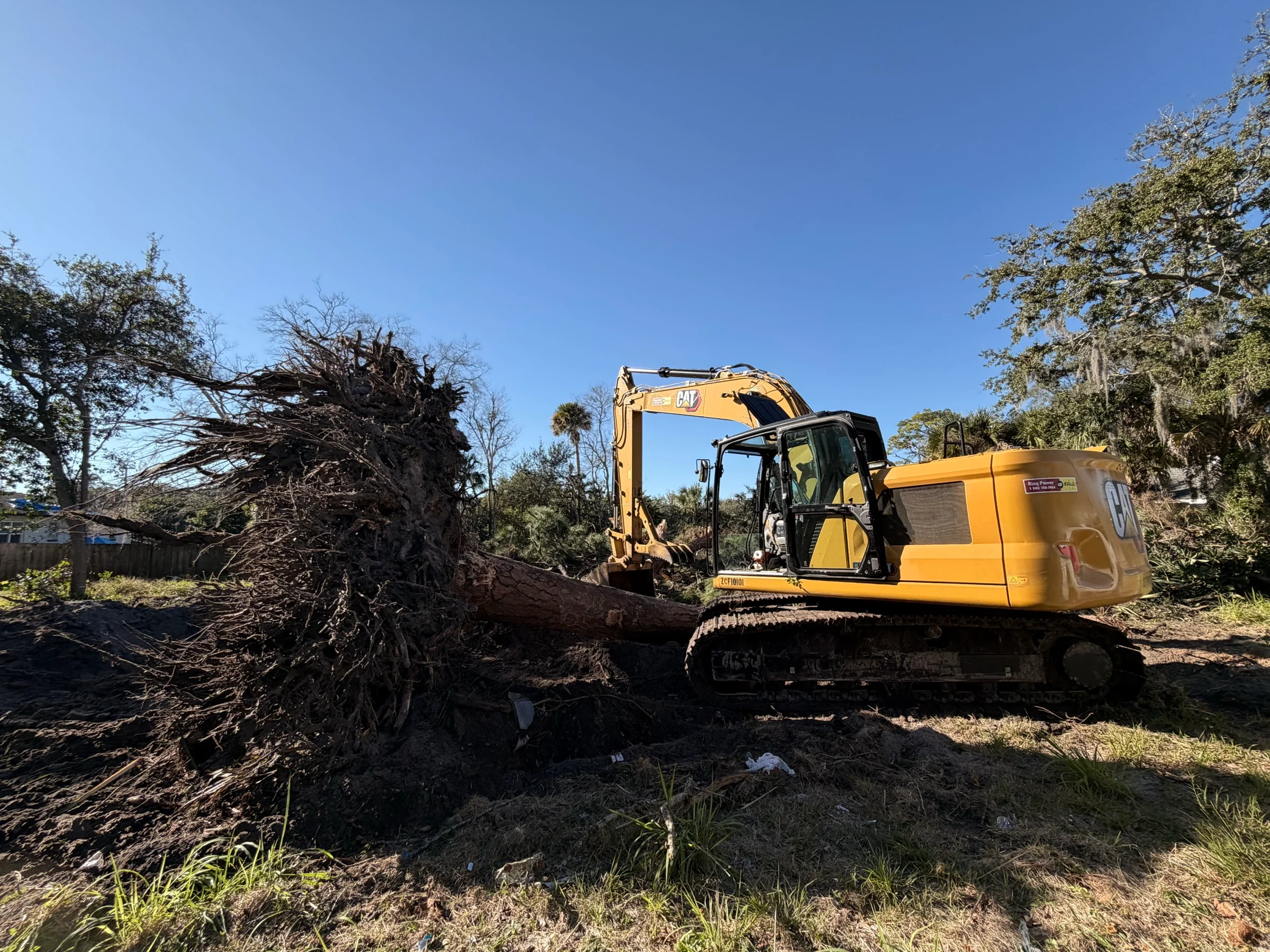 CAT excavator with grapple rake handling land clearing debris
